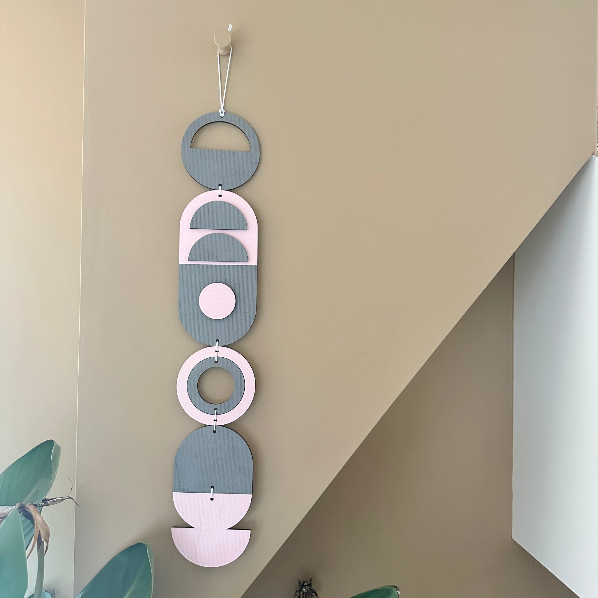 A vibrant pink and grey handmade geometric wood wall hanging. Featuring a textured effect through layer wood pieces and laser etching. Measuring 68cm in length x 10cm wide