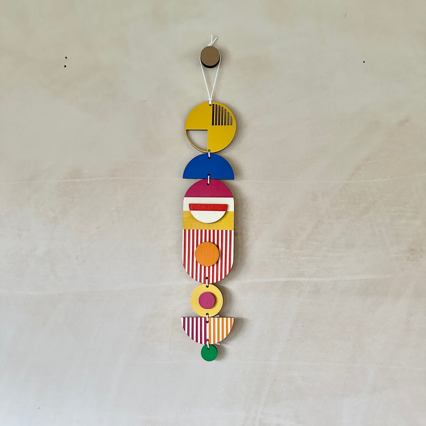 Style 1 of the wall hangings in a rainbow colour palette made from wood cut in to geometric shapes.
