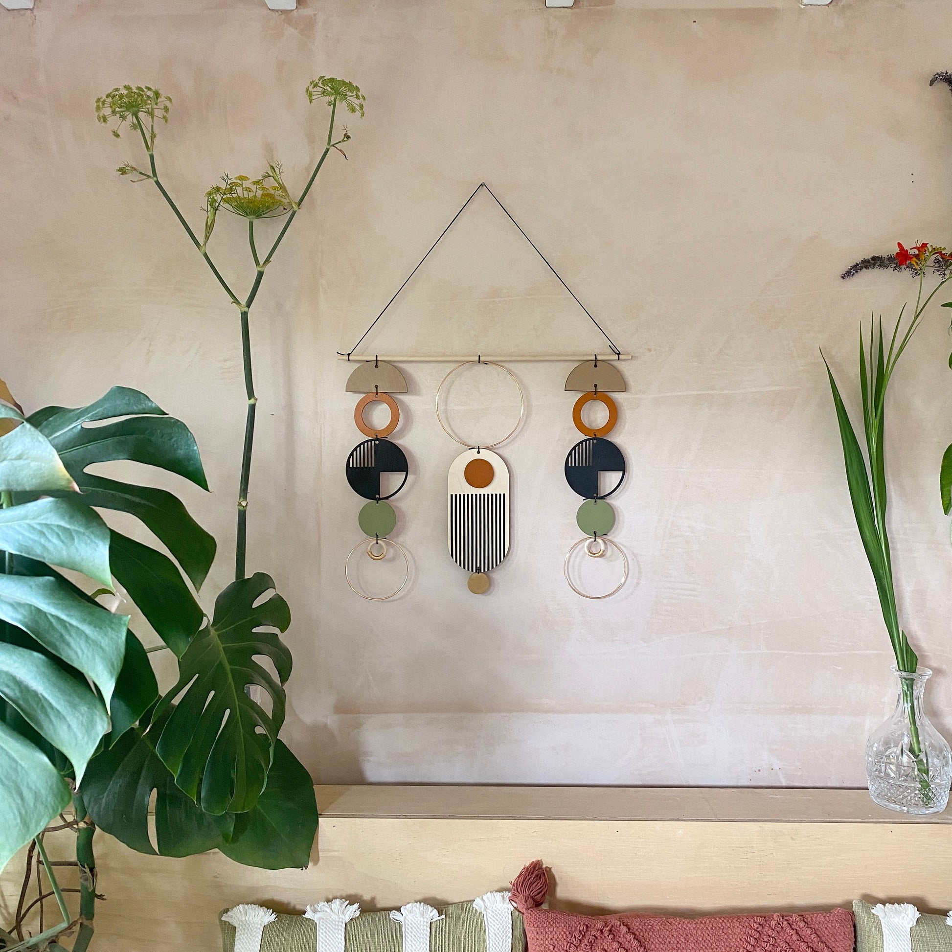 A wall hanging in a mid century modern style. Made from geometric plywood shapes painted in orange, green and black with gold metal coloured accents. Measuring - 66cm (26”) long, 32cm (13”) wide.