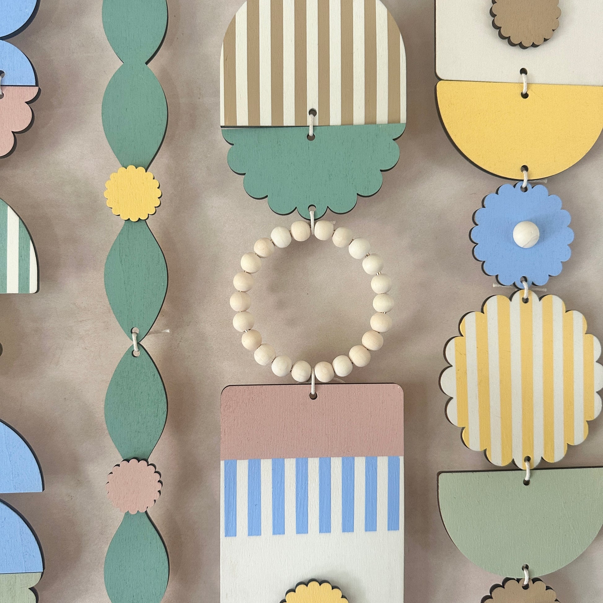 a large botanical inspired wall art piece made from plywood. The plywood is cut in floral and geometric shapes and painted in blue, yellow, green, pink and brown.