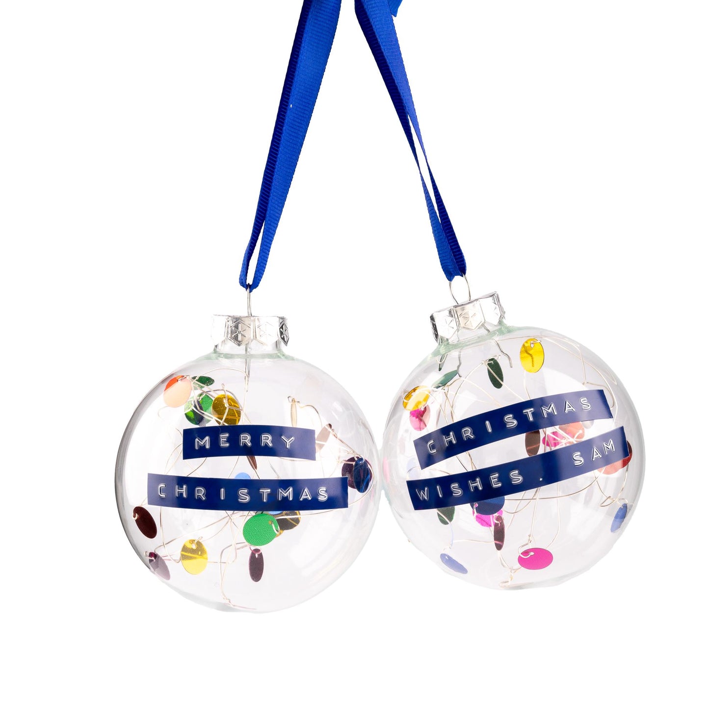 Glass baubles with a rainbow colour palette of sequins on silver wire inside with a blue ribbon to hang it from. With a personalised message embossed on blue tape.